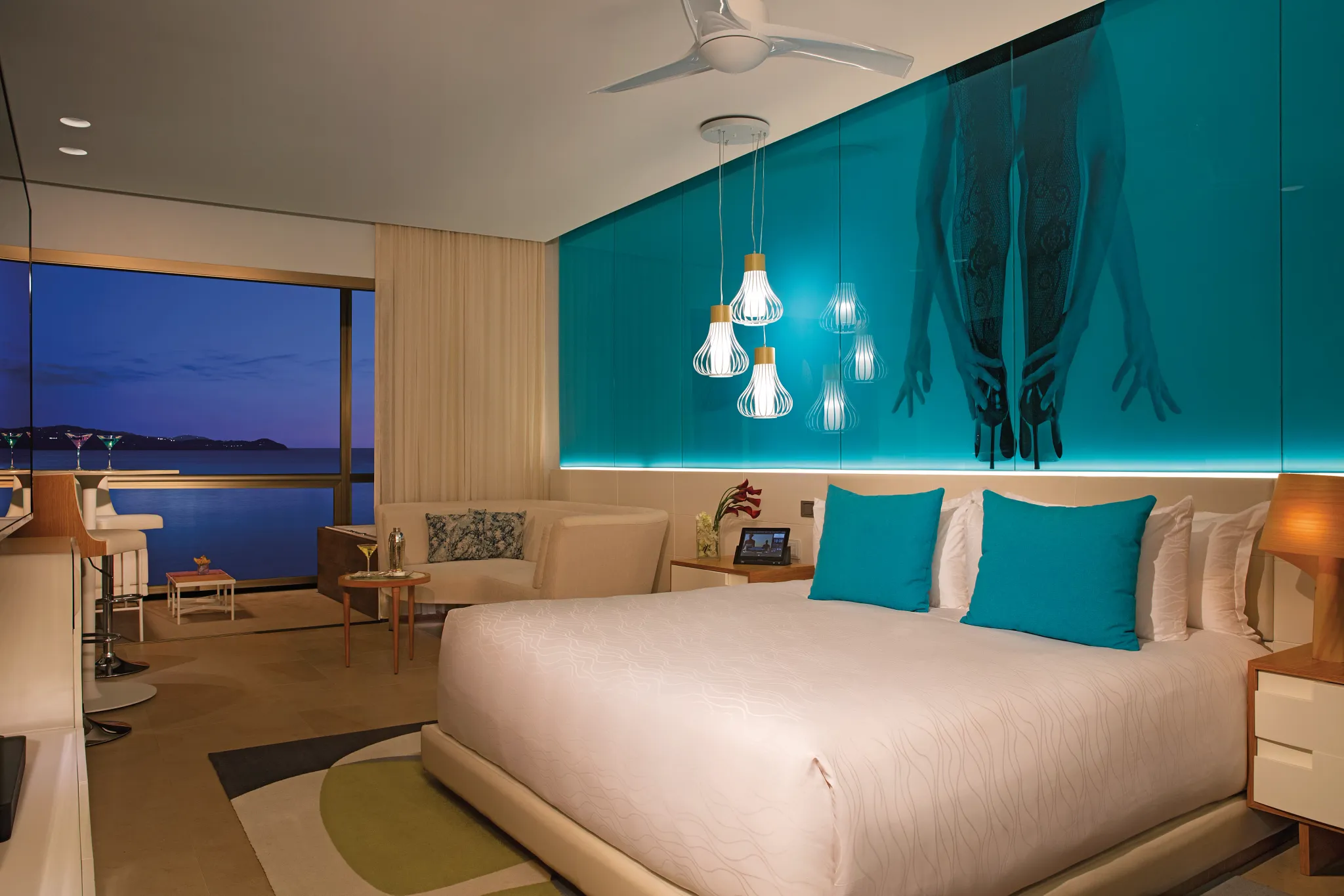 Night view of the Xhale Club Junior Suite Ocean View at Breathless Montego Bay with ambient blue lighting and balcony overlooking the bay.